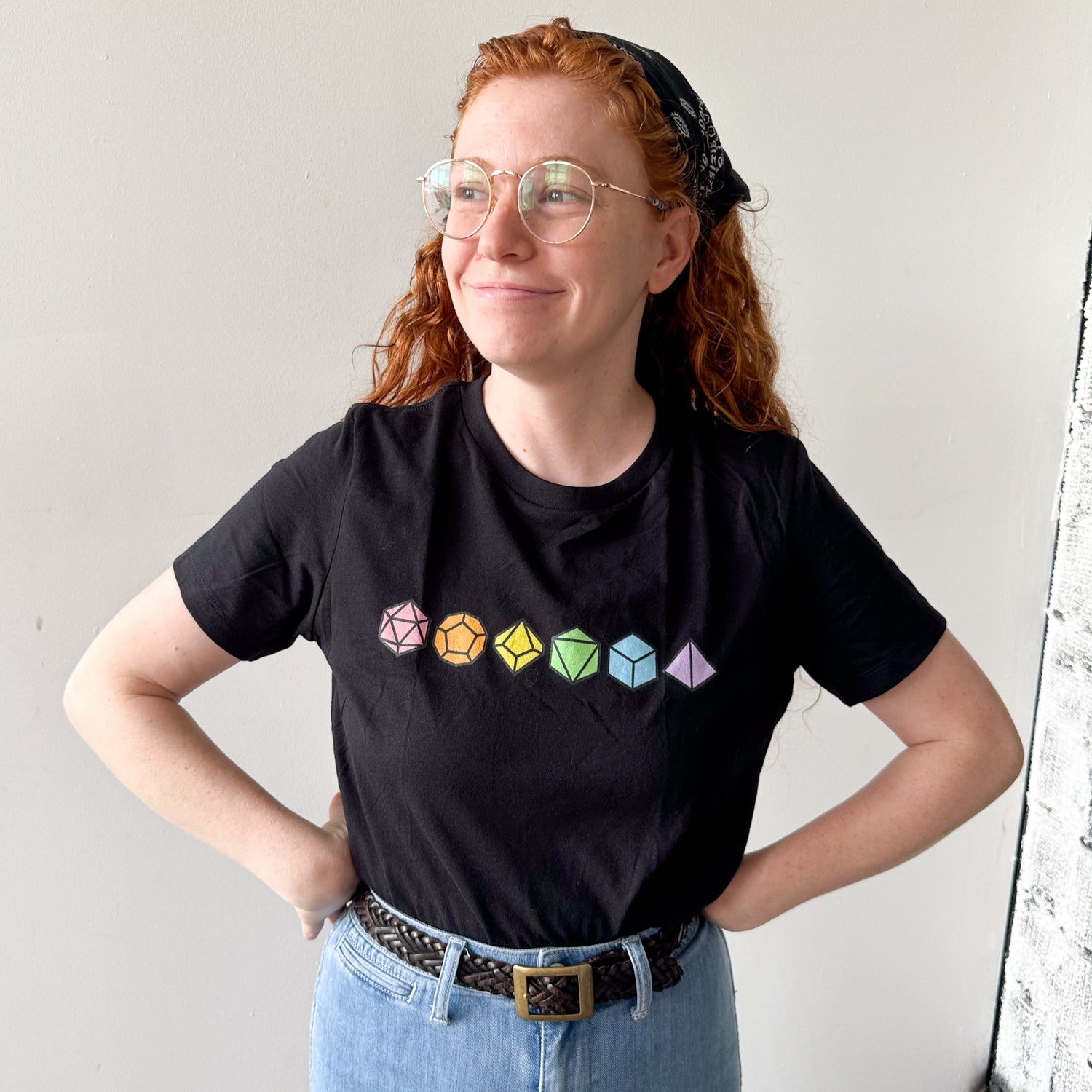 Person wearing a black short sleeve t-shirt that as a set of pastel rainbow dice on it.