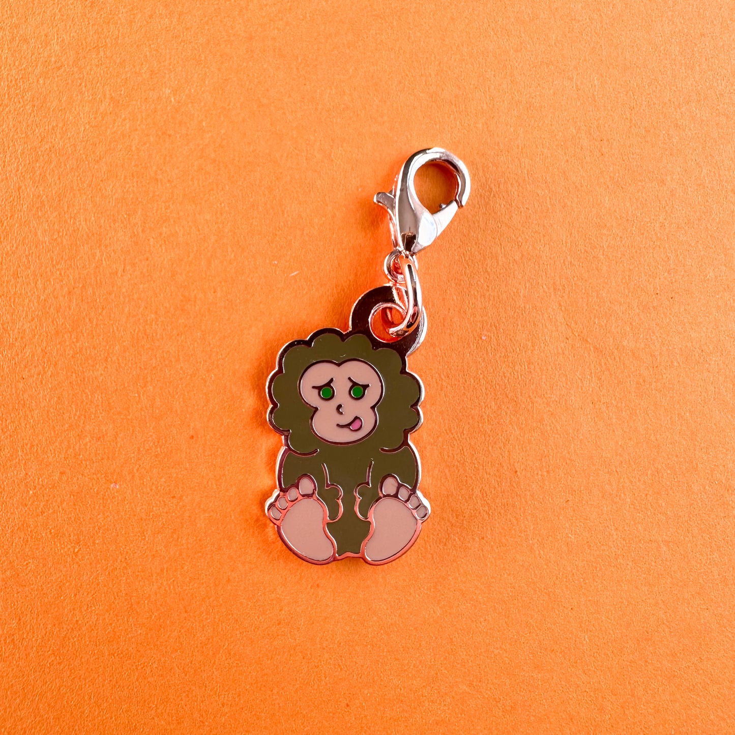 A charm in the shape of a cute illustration of Bigfoot with a lobster claw clasp.