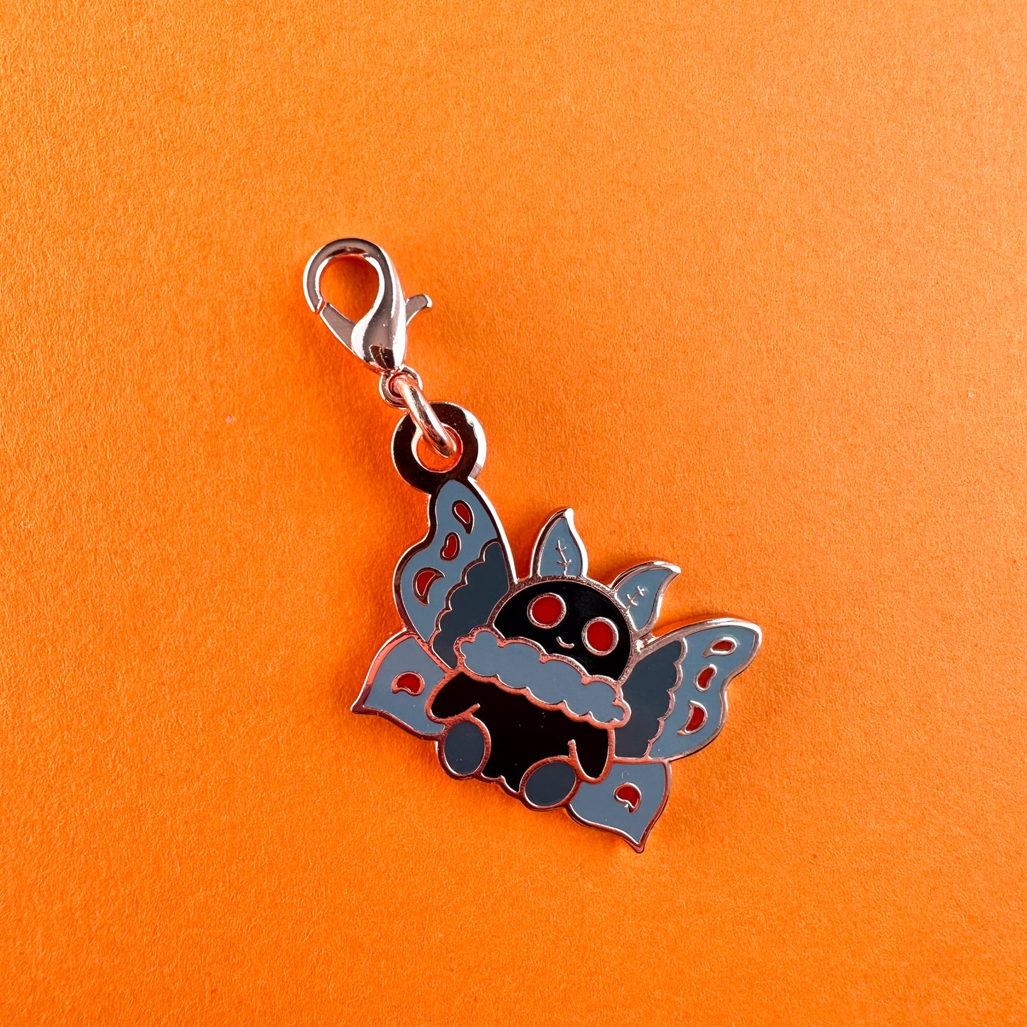 Mothman in a cute cartoon illustrative style as a little charm with a lobster claw clasp.