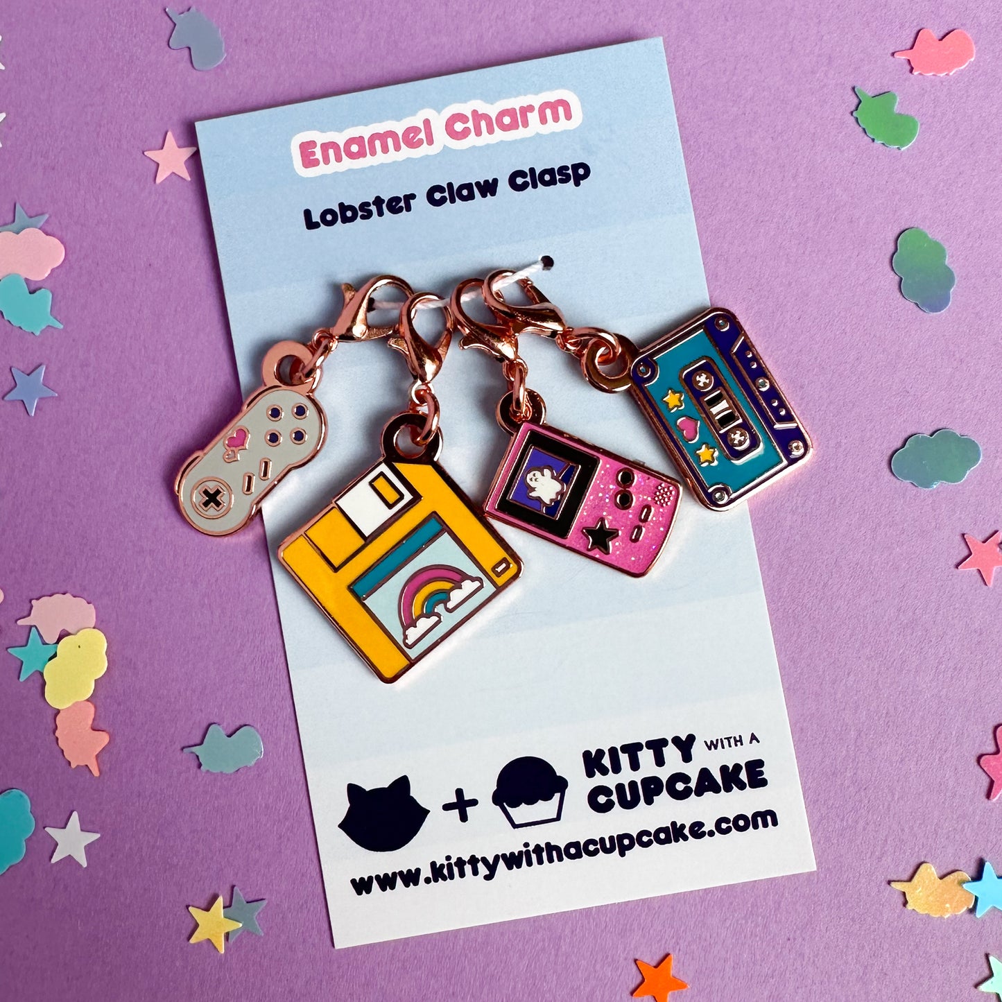 A four pack of charms packaged on a blue card. The charms are shaped like a game console controller, floppy disk, gameboy, and a cassette tape.