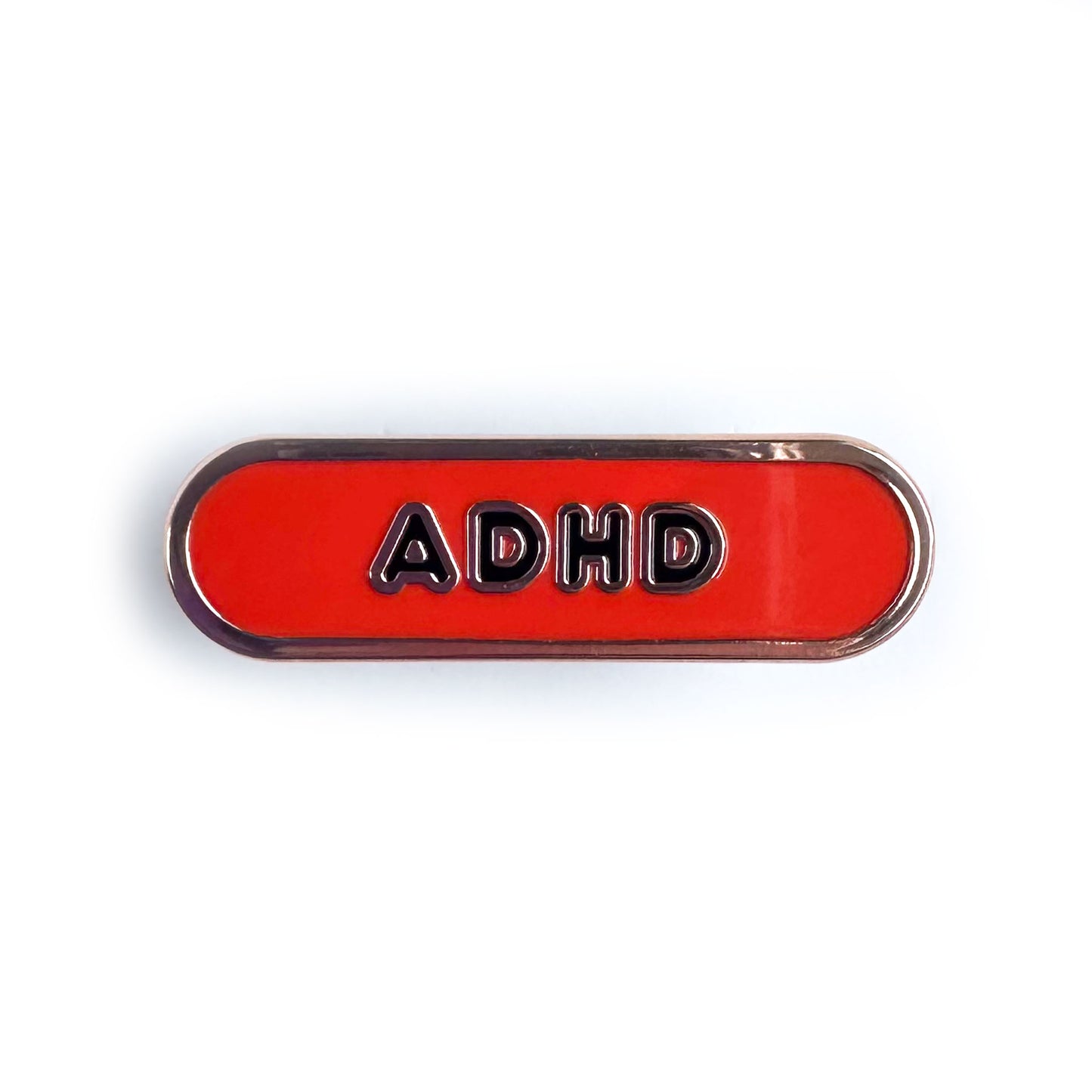 A red oval shaped enamel pin with the letters ADHD on it in black bubble letters.