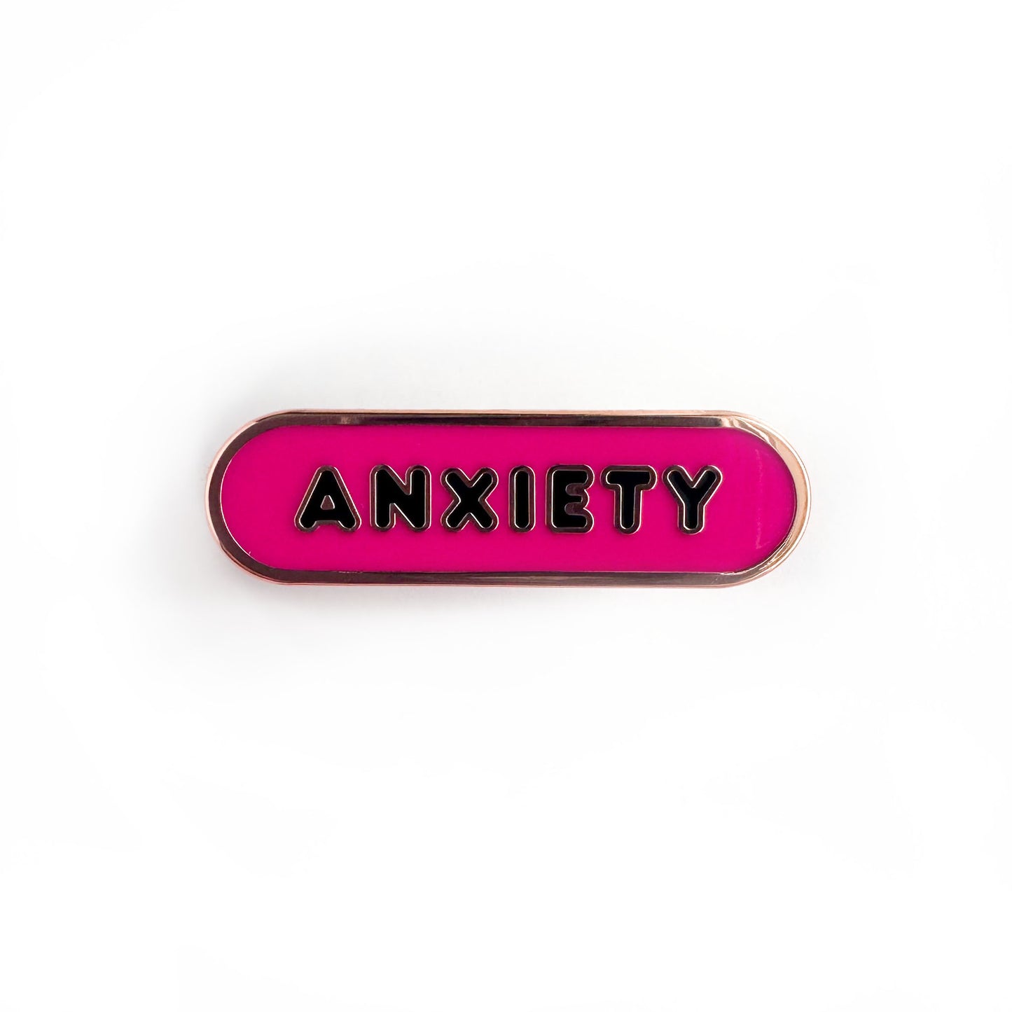 Oval shaped enamel pin with "anxiety" written in black text on a hot pink background.