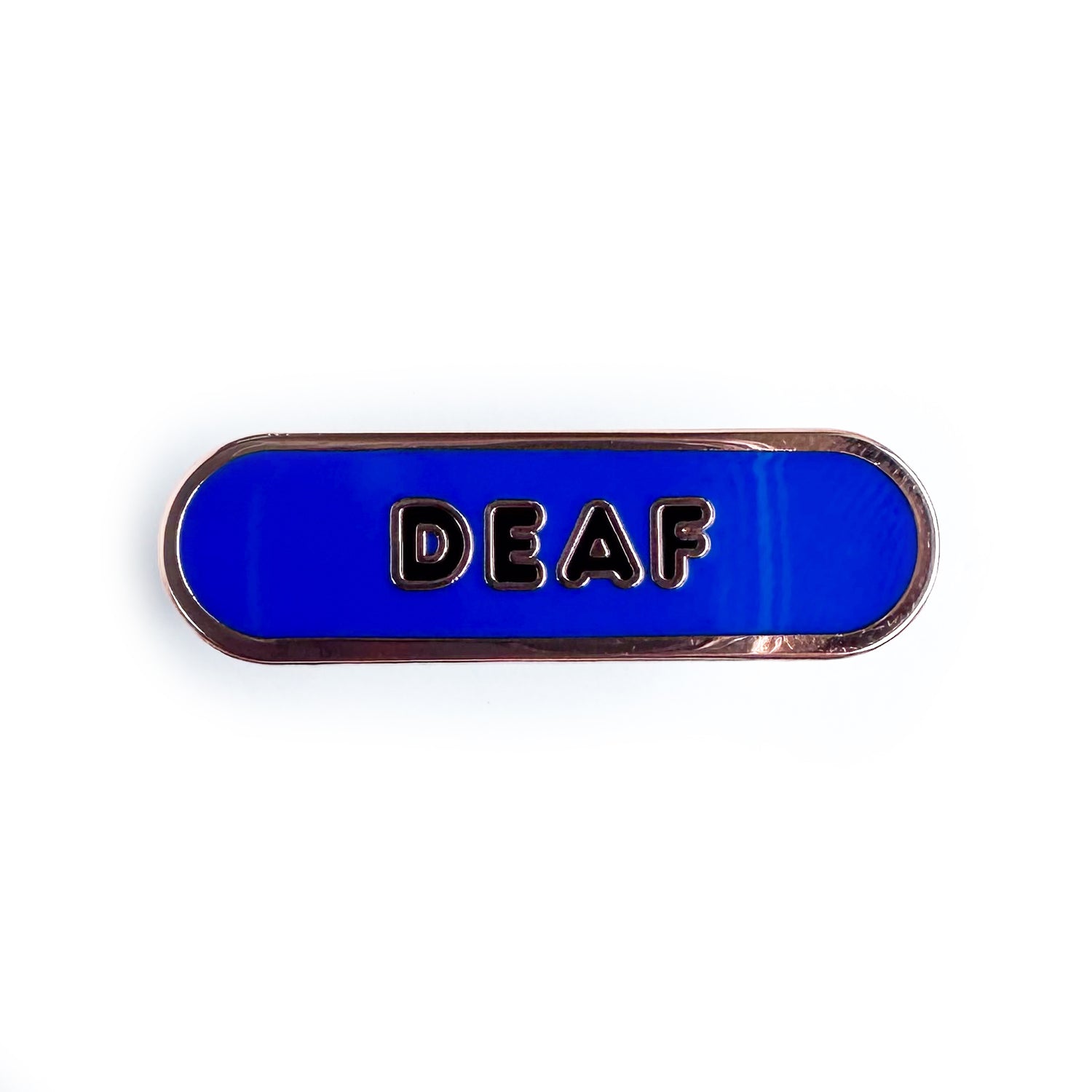 A blue capsule shaped pin with black bubble letters that spell "Deaf" on it.