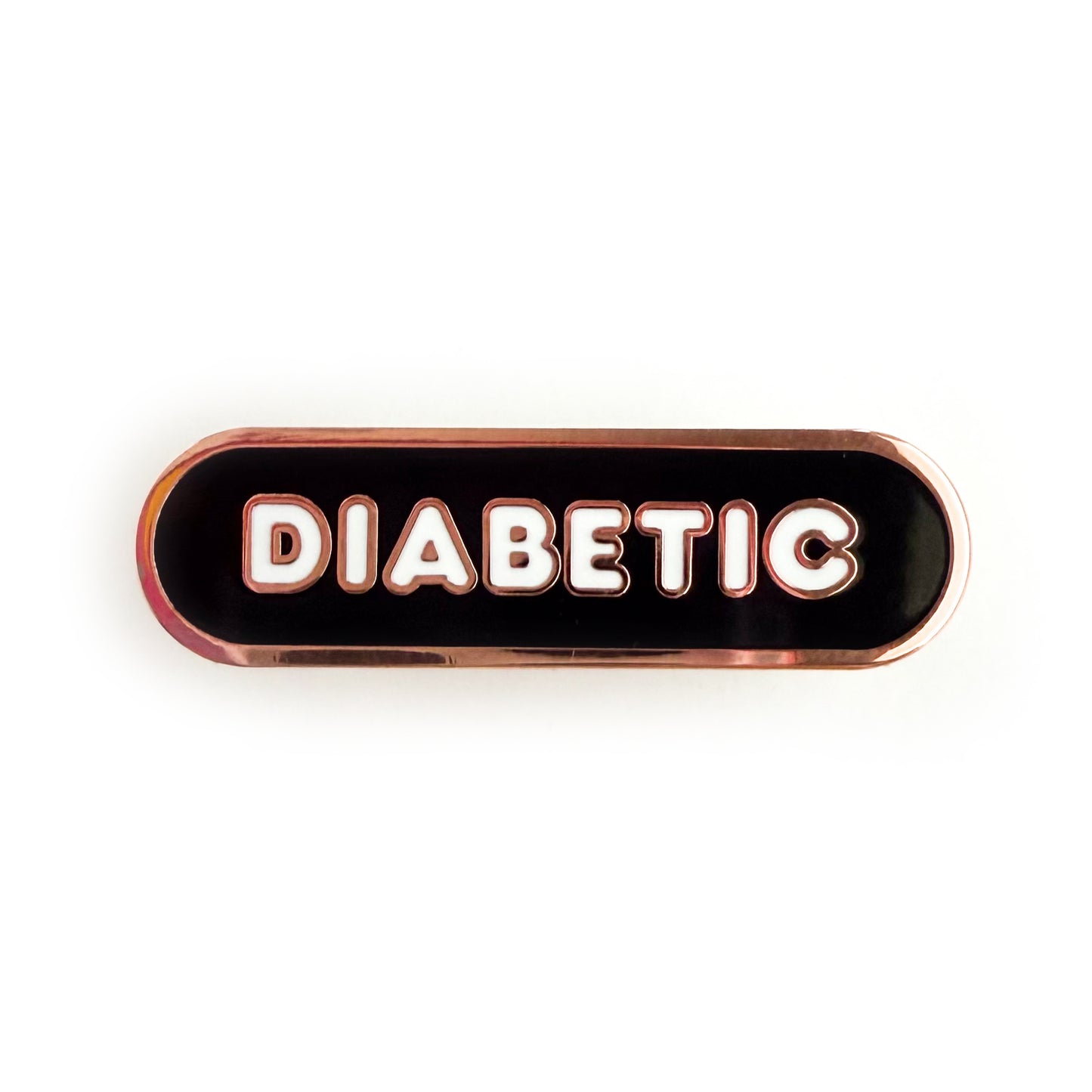 A bandaid shaped pin with the text DIABETIC in bubble letters. The background is black and the text is white.