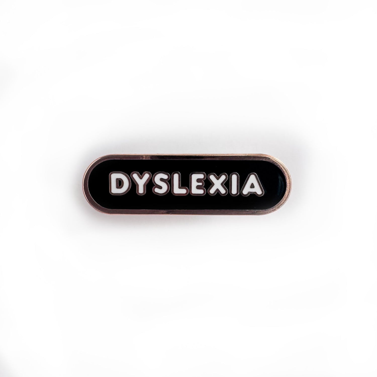 Oval shaped enamel pin with "dyslexia" written in white text on a black background.