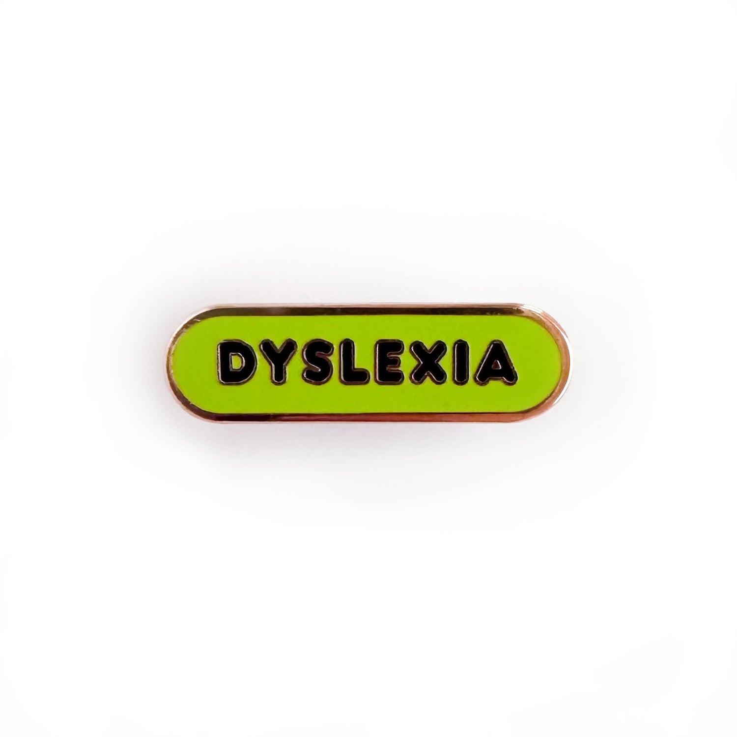 Oval shaped enamel pin with "dyslexia" written in black text on a lime green background.