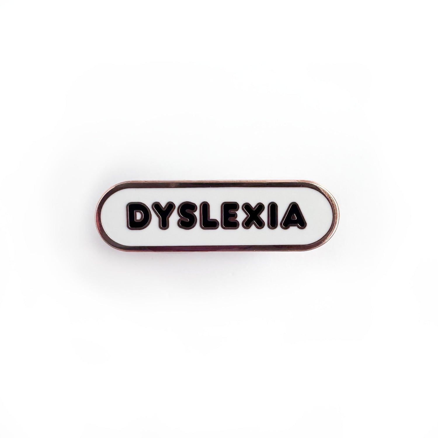 Oval shaped enamel pin with "dyslexia" written in black text on a white background.