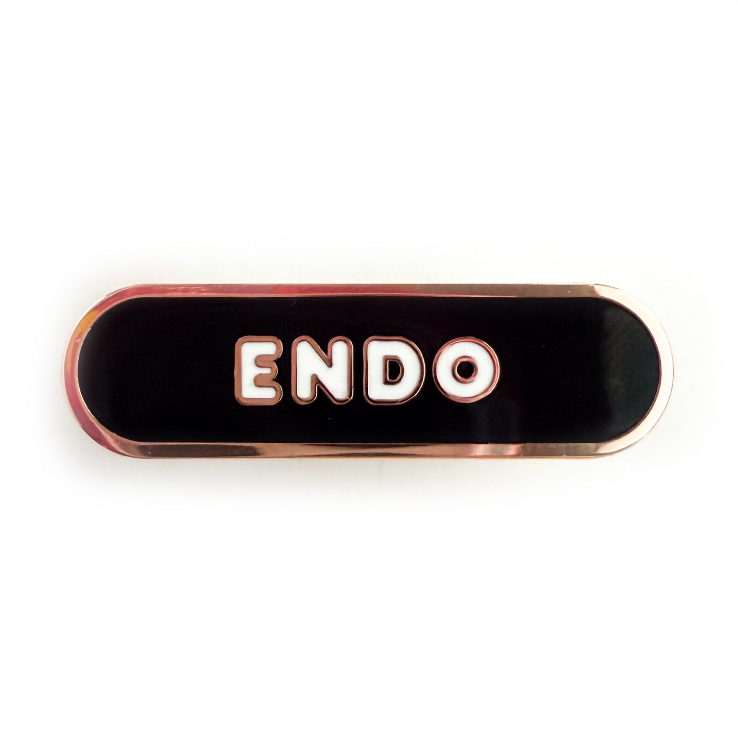 A bandaid shaped pin with the text ENDO in bubble letters. The background is black and the text is white.