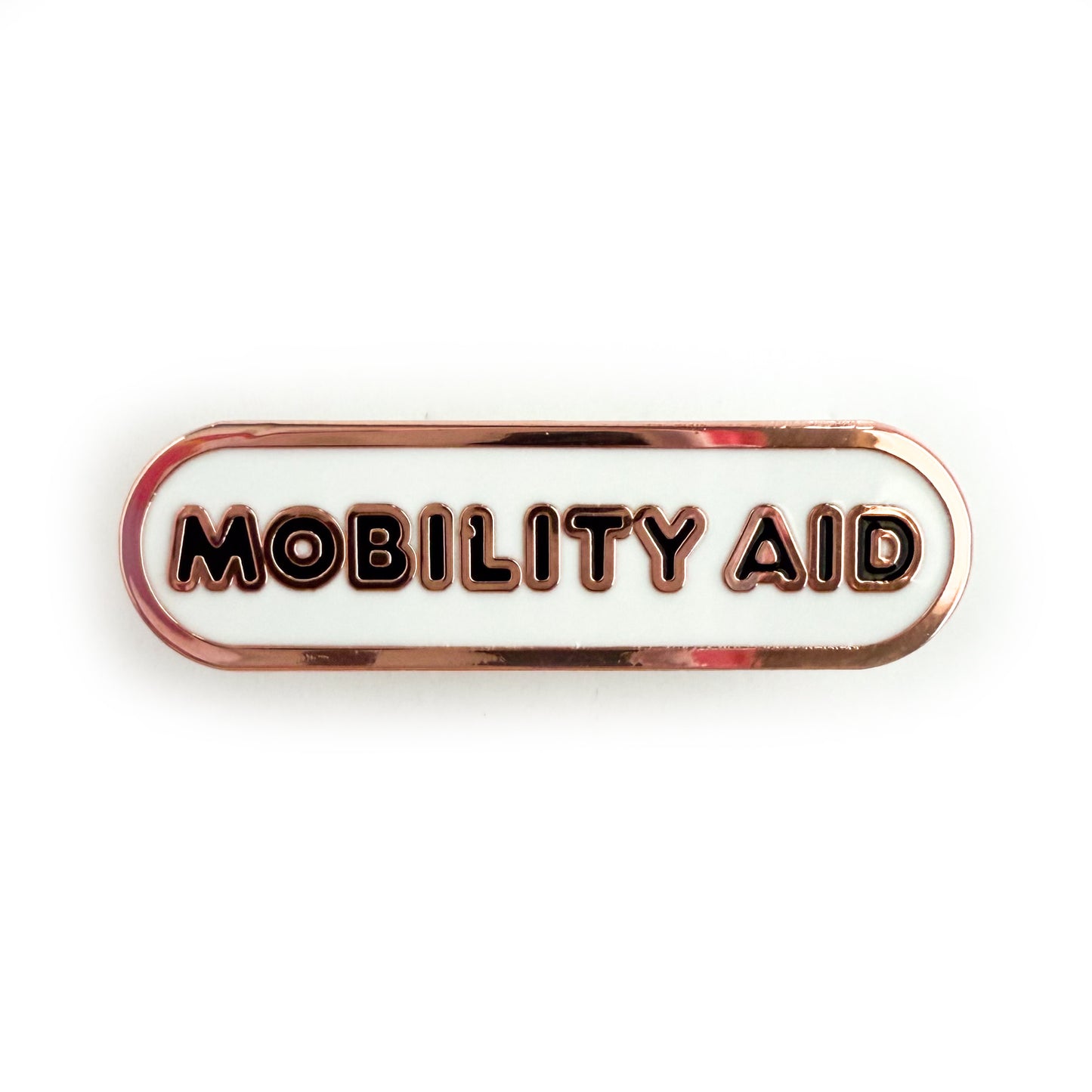 A bandaid shaped pin with the text MOBILITY AID  in bubble letters. The background is white and the text is black.