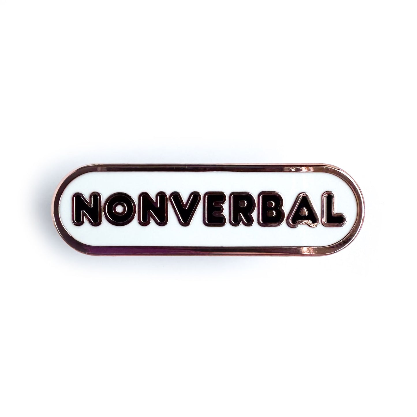 A white enamel pin in the shape of a bandaid that has black bubble letters that spell "Nonverbal".