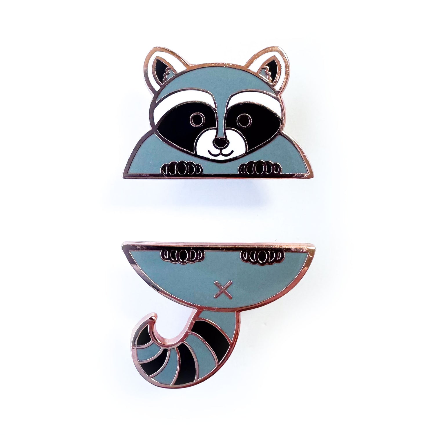 Two enamel pins that come together in the middle to form a cute raccoon, the top pin is the head and front paws and the bottom pin is the tail and back paws.