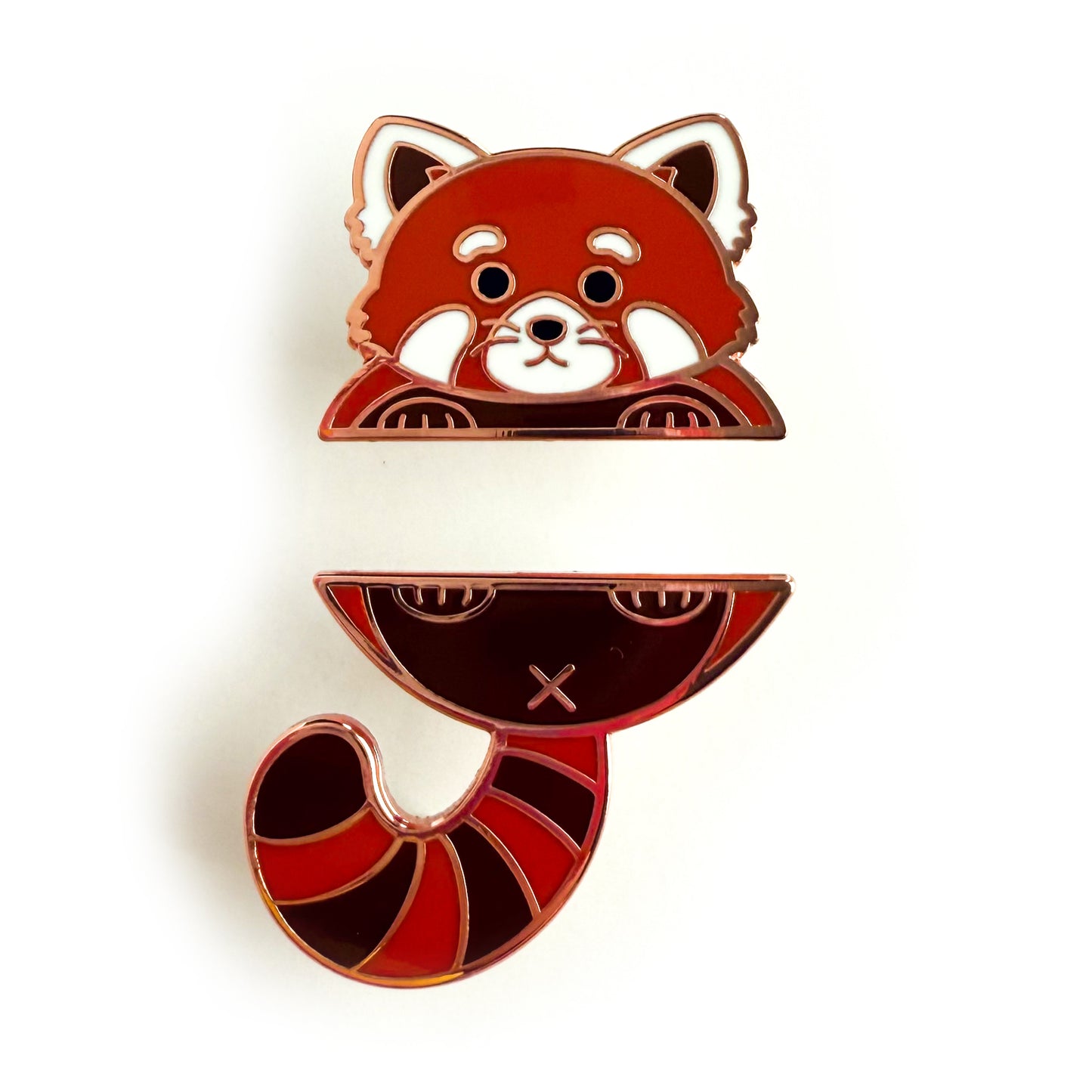 A two piece pin set that comes together to form a red panda. The top pin is the red panda’s top paws and head. The bottom pin is the red panda’s butt, stripped tail, and feet.