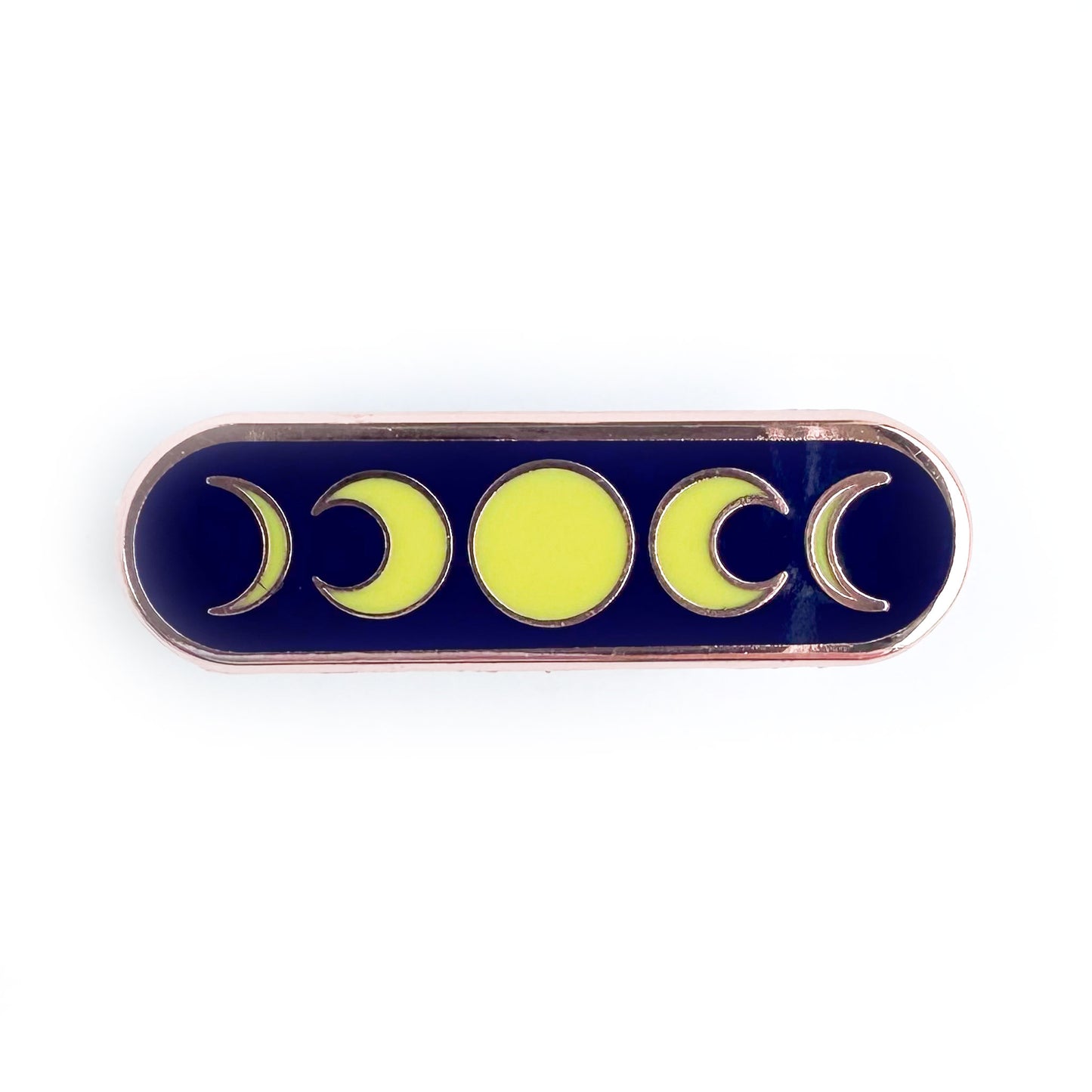 A capsule shaped pin with a dark blue background with yellow illustrations of moon phases on it.