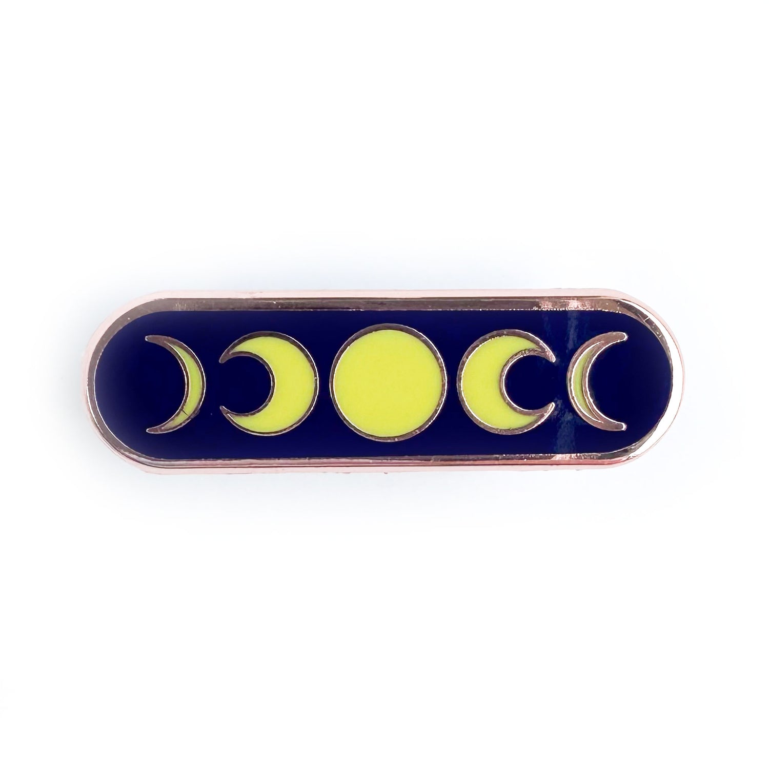 A capsule shaped pin with a dark blue background with yellow illustrations of moon phases on it.