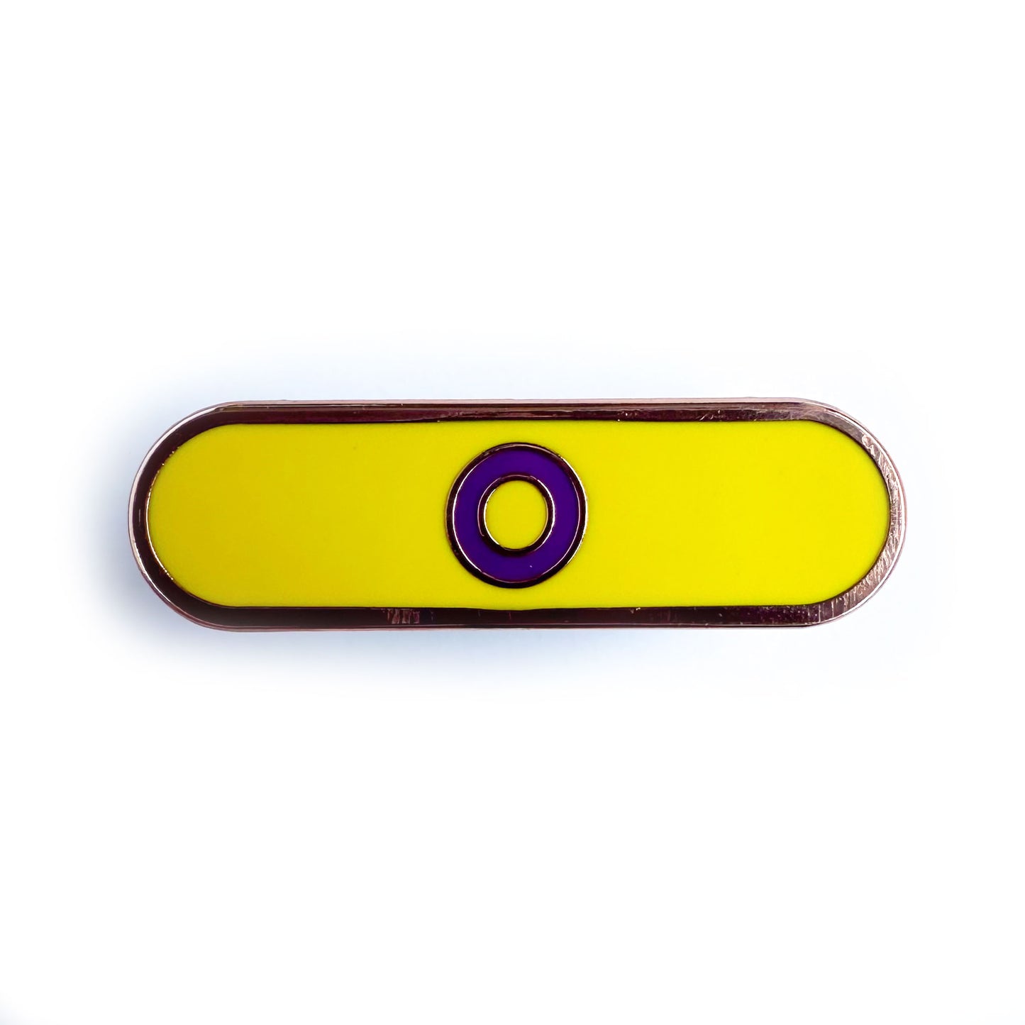 A capsule shaped pin that has a purple circle on a yellow background to represent the Intersex Pride Flag.