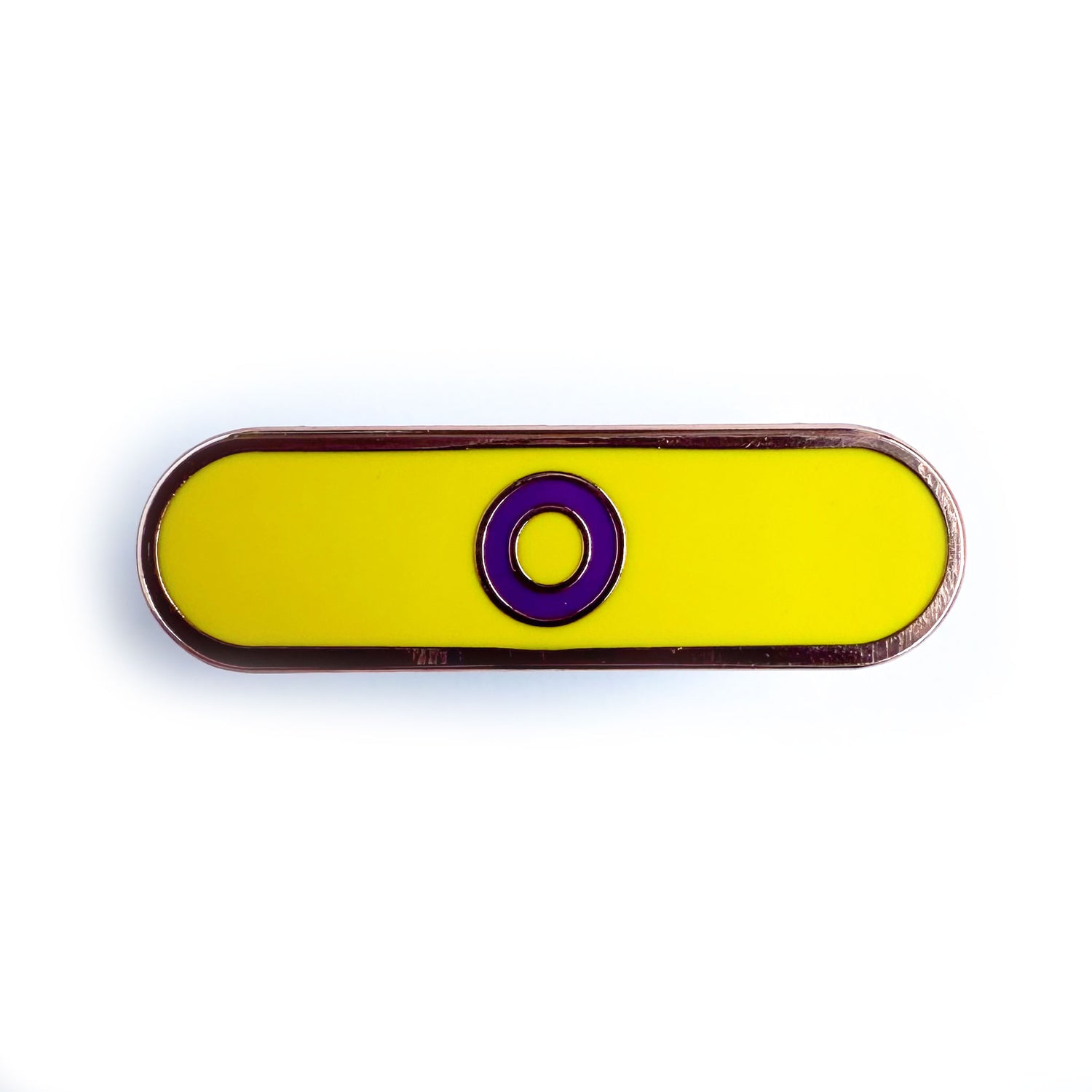 A capsule shaped pin that has a purple circle on a yellow background to represent the Intersex Pride Flag.