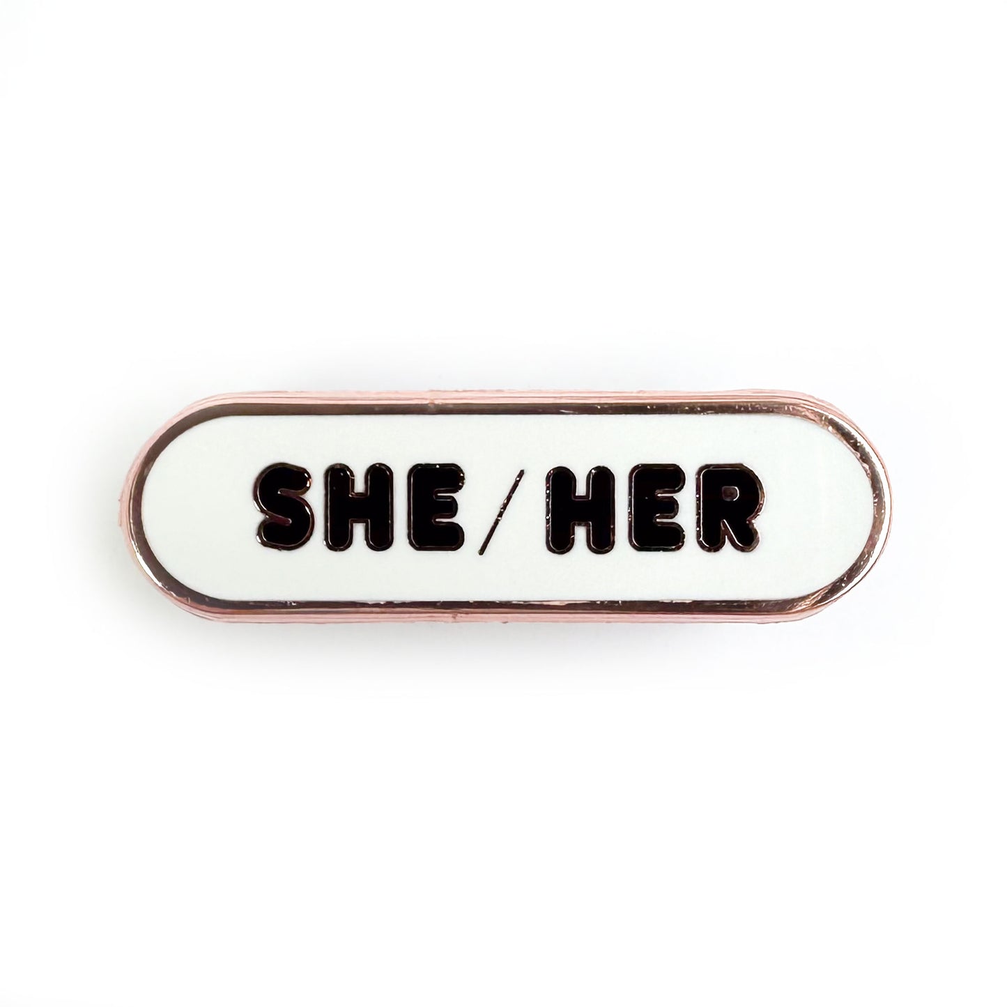A capsule shaped pin with a white background and black letters that spell "She/Her".