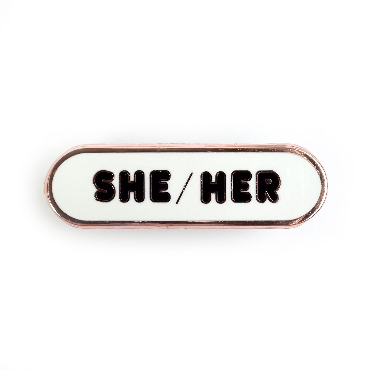 A capsule shaped pin with a white background and black letters that spell "She/Her".