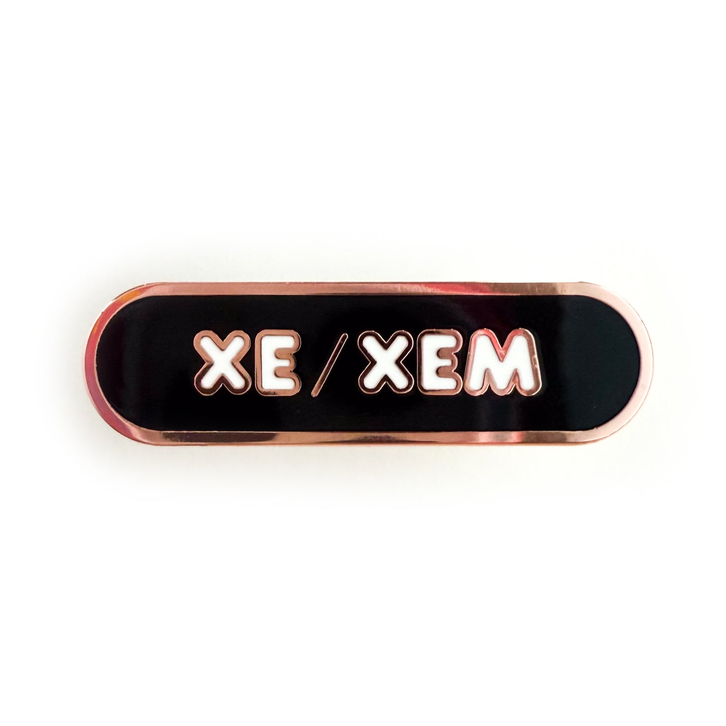 A bandaid shaped pin with the text XE/XEM in bubble letters. The background is black and the text is white.