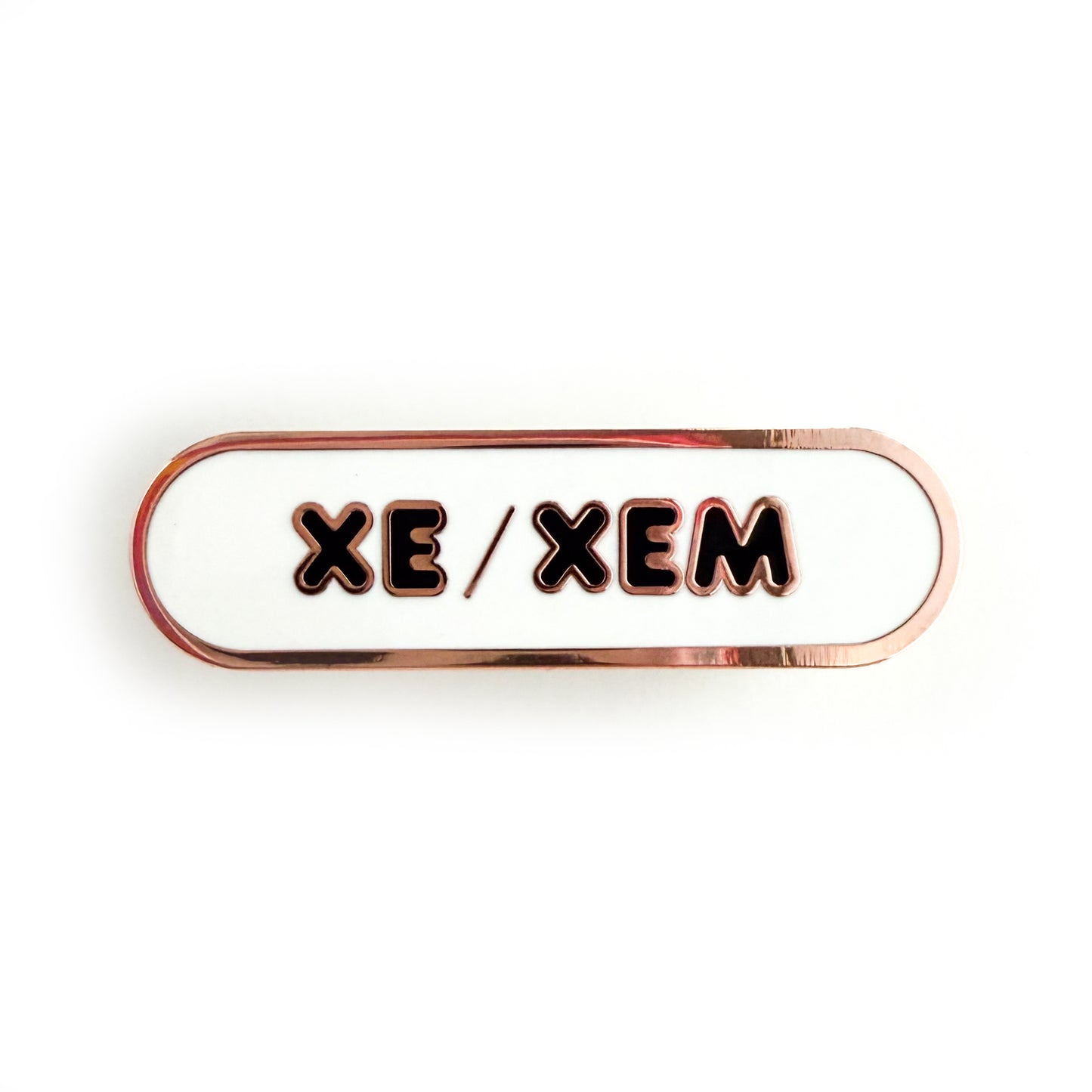 A bandaid shaped pin with the text XE/XEM in bubble letters. The background is white and the text is black.