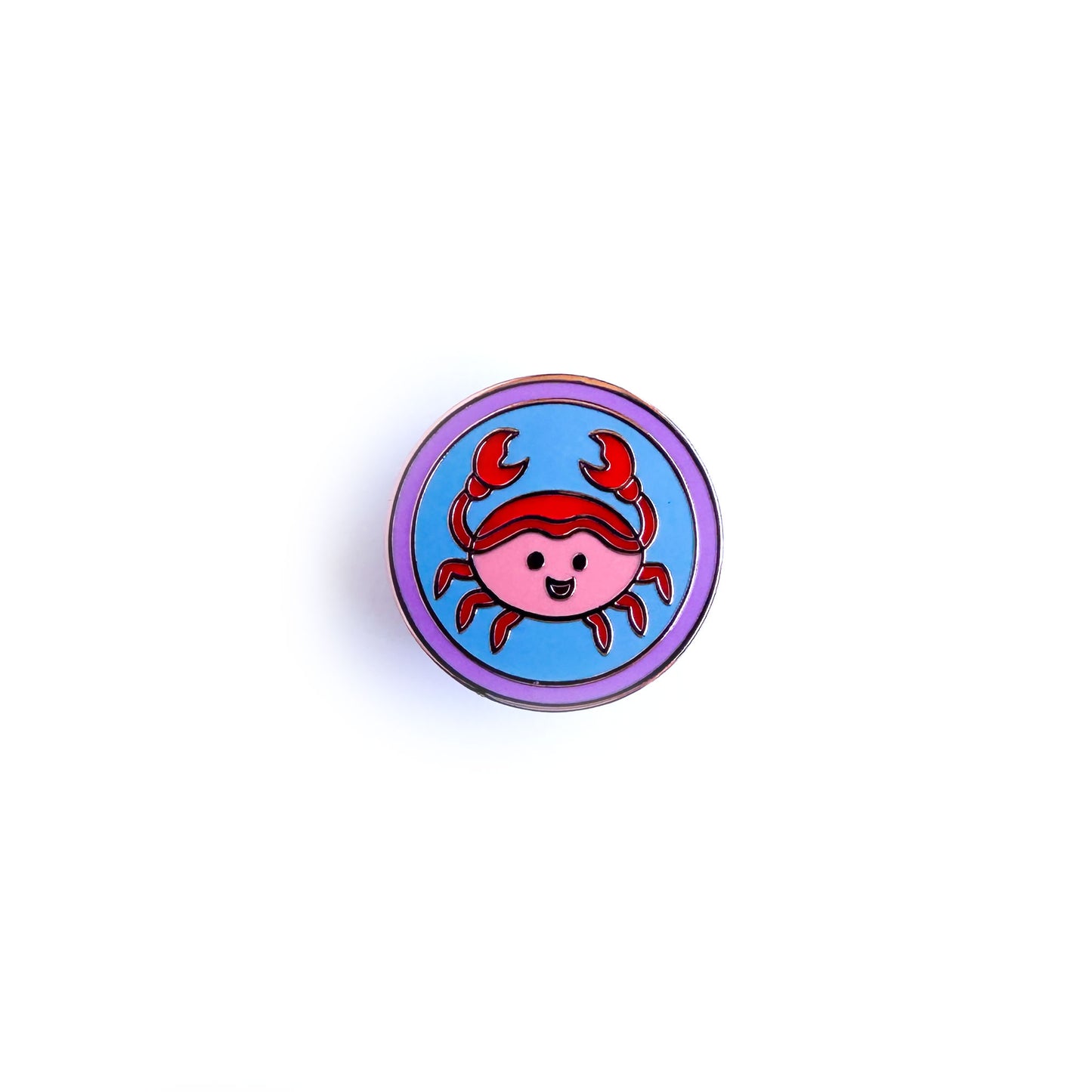 A circular enamel pin with a cute crab design inside to represent the Cancer astrological sign.