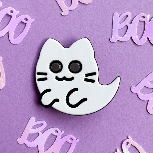 A ghost kitty hair clip made from white and black acetate on a lavender background covered in "Boo" confetti.