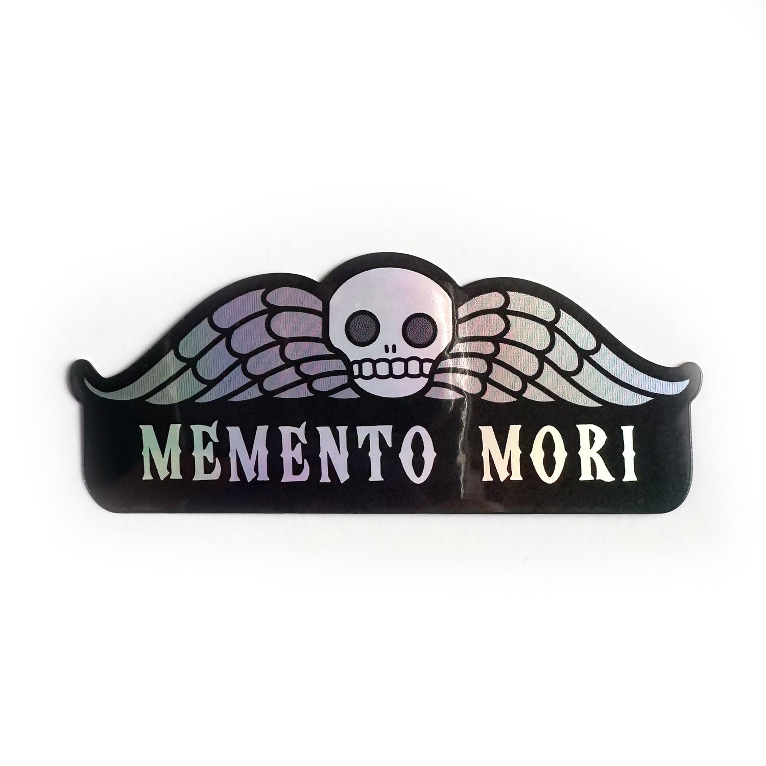 A sticker with an illustration of a deaths head gravestone (a skull with wings) with the words Memento Mori underneath it.