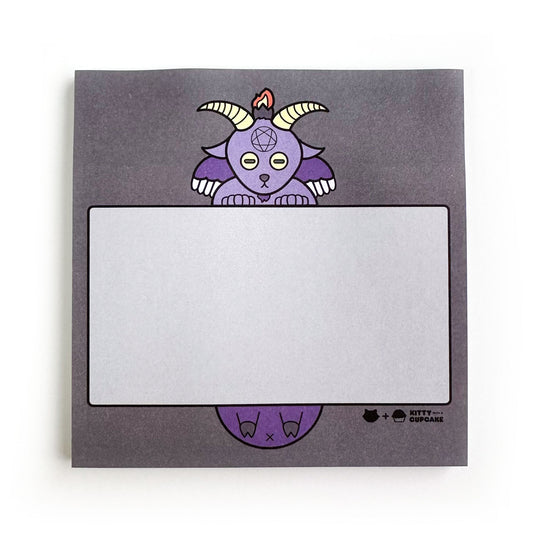 A square pad of sticky notes that are charcoal with a cute illustration of Baphomet on them, he is holding a light grey box to write in.