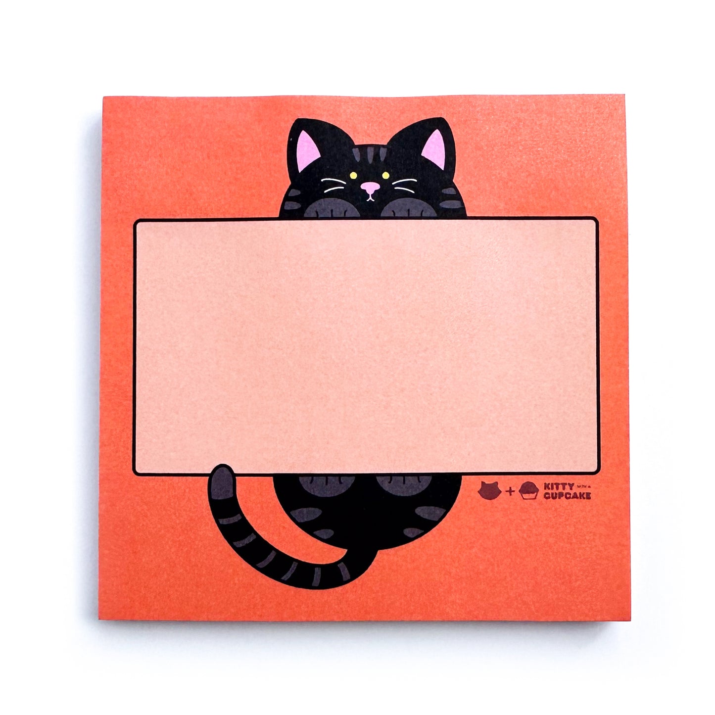 A pad of square orange sticky notes featuring a lighter orange rectangle for writing with a cute illustration of a cat holding this rectangle. The cat is black and it's head is above the rectangle and it's butt is below the rectangle