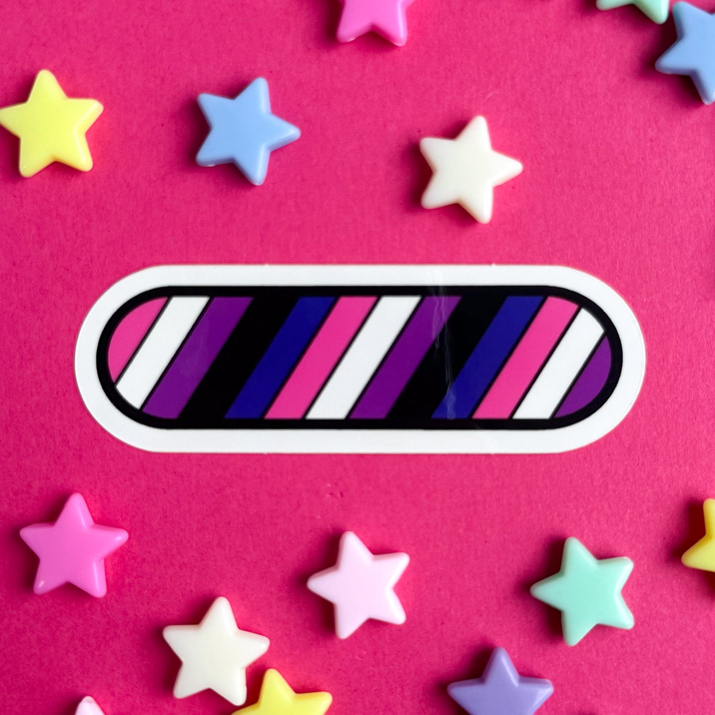 A sticker with stripes of the Gender Fluid Flag in diagonal lines. The sticker is on a pink background with pastel star beads around it.