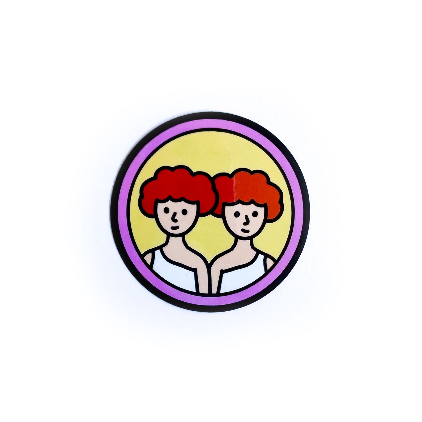 A circular sticker with twins with red hair on it to represent the Gemini Zodiac sign.