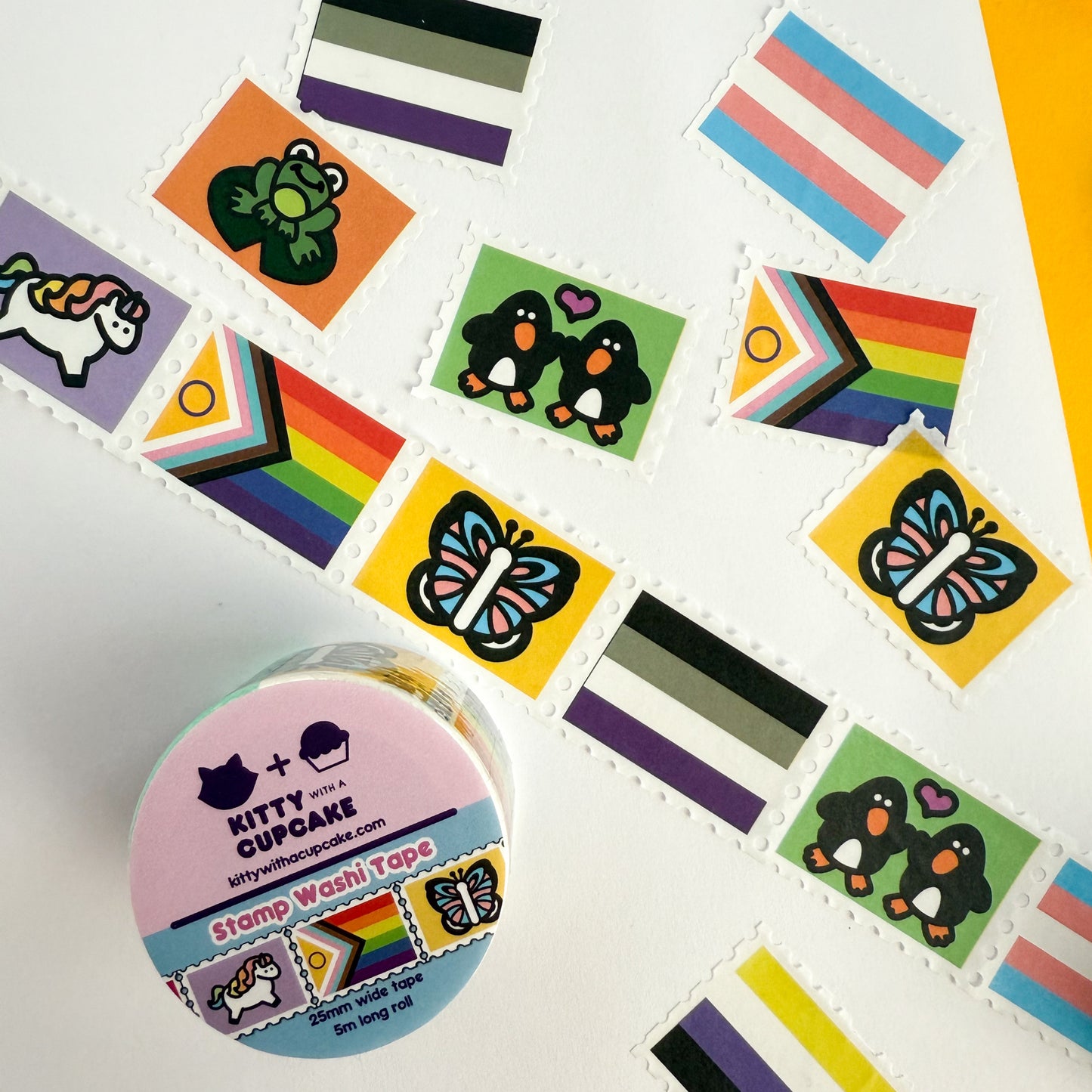 A roll of pride themed stamp washi tape. There is a packaged roll of tape with the Kitty With a Cupcake logo and an example of the tape inside. Above this is a displayed section of the tape, which is sectioned into stamp-style squares, and above that is more individual stamp squares displayed.