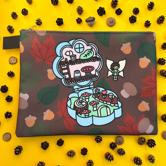 A flat zipper bag with an illustration of a fairy polly pocket toy on it. The back is on a yellow background covered in pinecones and acorns.