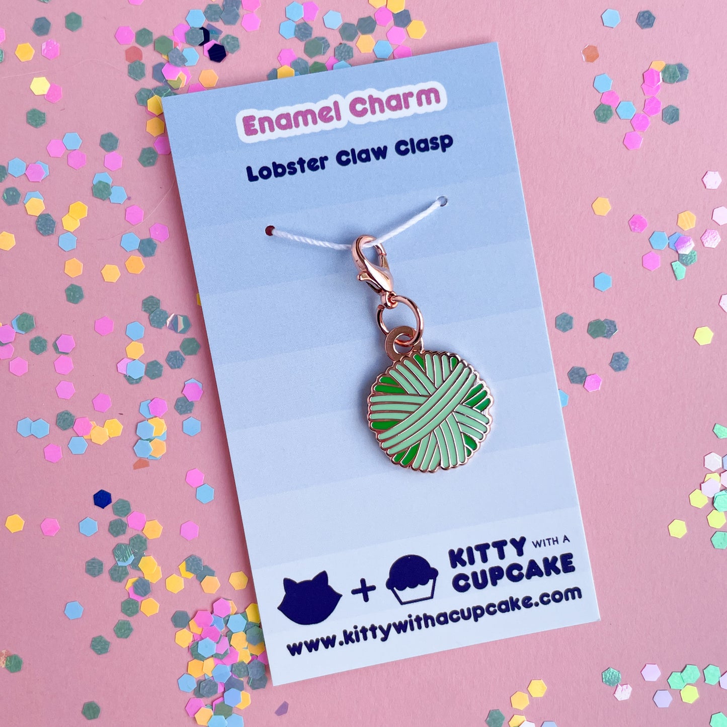 A mint green yarn ball charm on a blue card.
