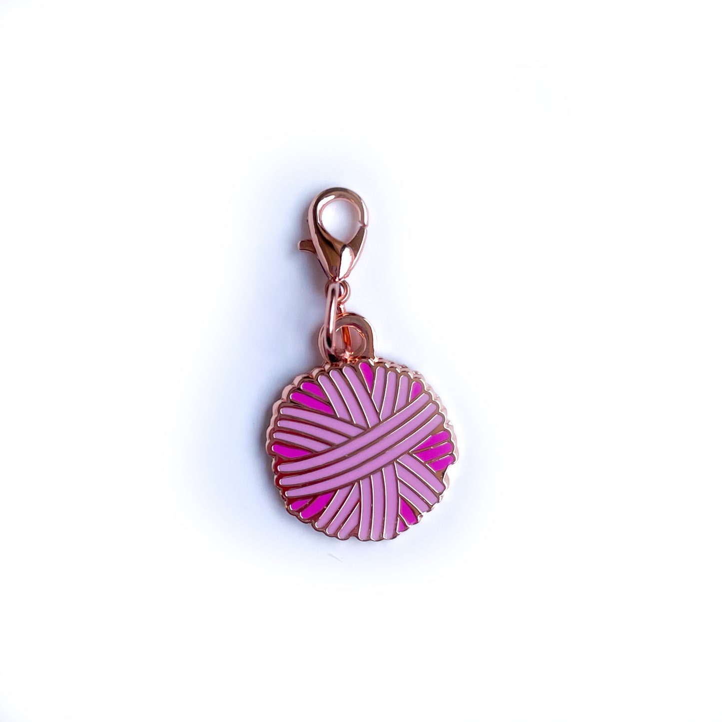 A yarn ball shaped charm in shades of pink with a lobster claw clasp. 
