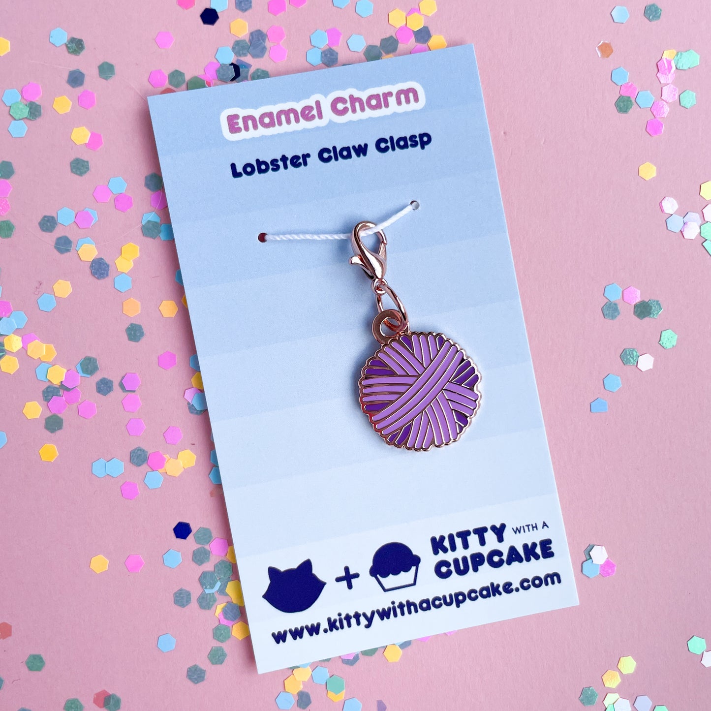 A purple yarn ball charm on a blue card.