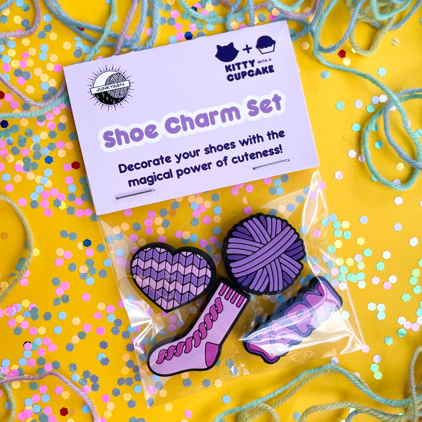 A plastic bag with a header card that reads "Shoe charm set". The bag has charms in it shaped like a heart, yarn ball, sock, and the word yarn.