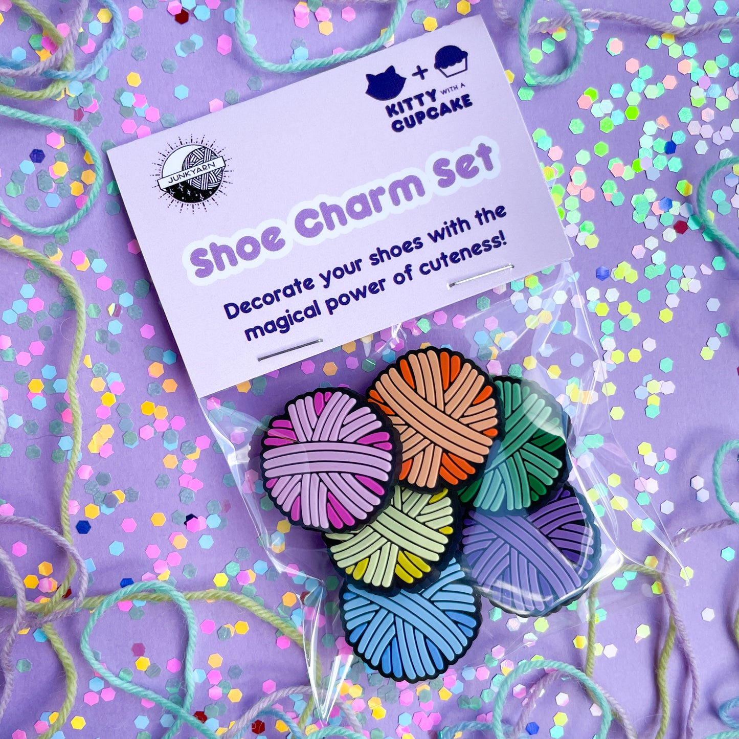 A bag with a pink header card that reads "shoe charm set" there are yarn ball charms in the bag.