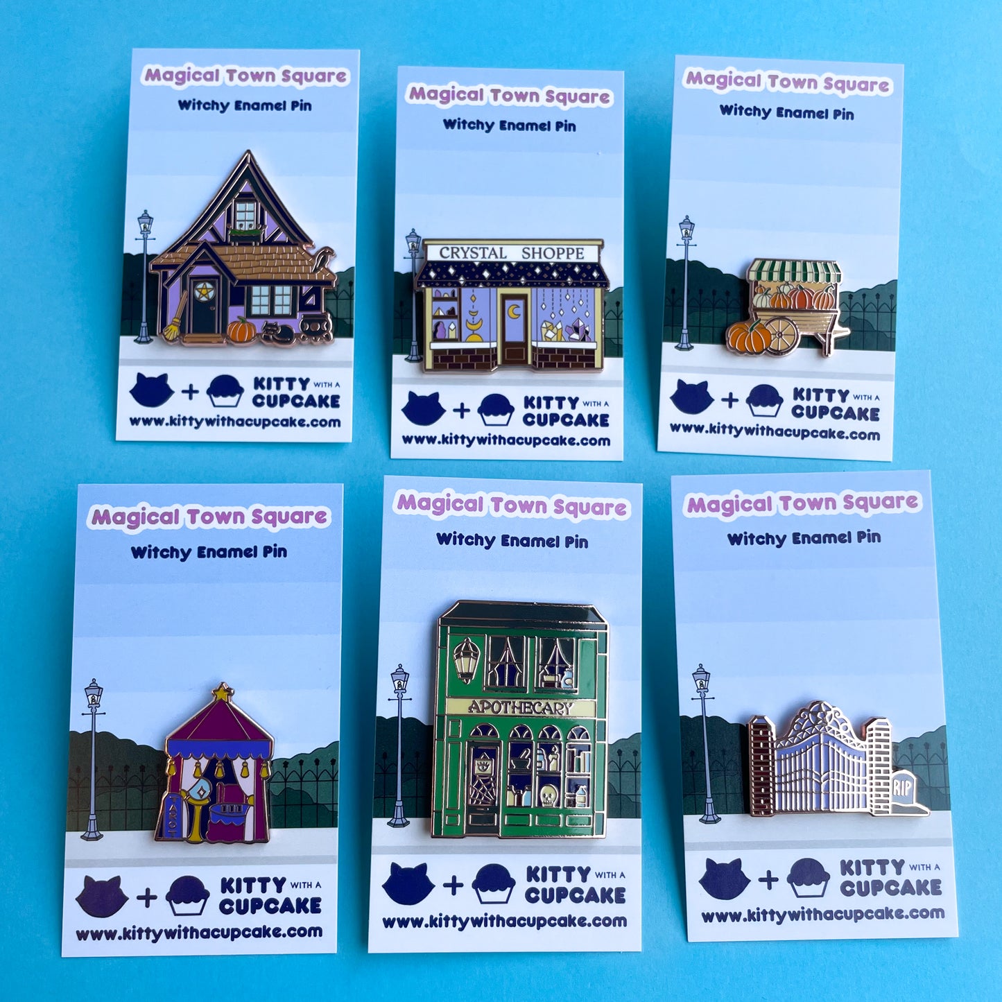 The full magical town square pin set displayed on display cards with an illustration on a sidewalk and street lamp