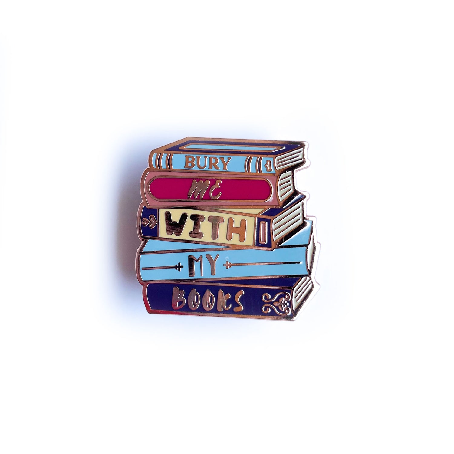 An enamel pin that is shaped like a stack of books that reads "Bury Me With My Books"