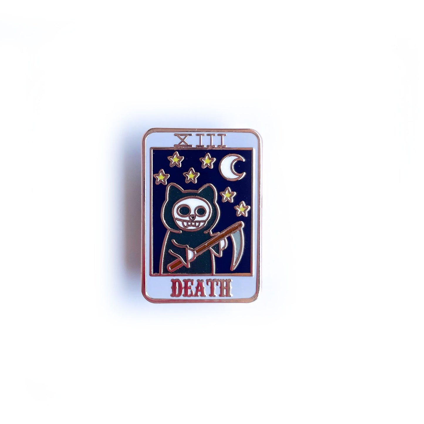 An enamel pin shaped like a tarot card with a grim reaper cat with a night sky on it and the word "Death"
