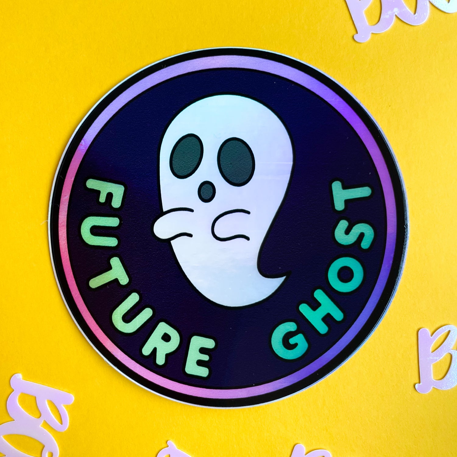 A circular holographic sticker that reads "Future Ghost" with a ghost on it on a yellow background.