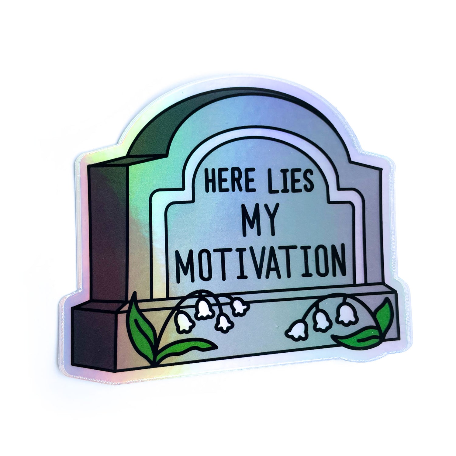 A gravestone shaped sticker that reads "Here Lies My Motivation" with lily of the valley flowers in front of it