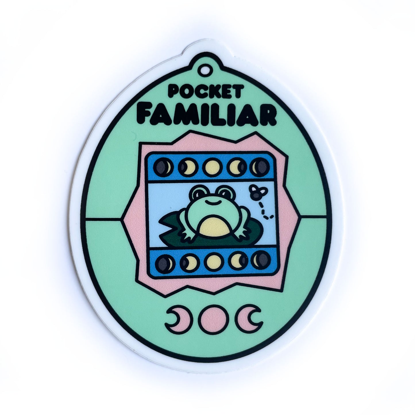A vinyl sticker shaped like a virtual pet with a frog on the screen that has a mint and peach colored shell.