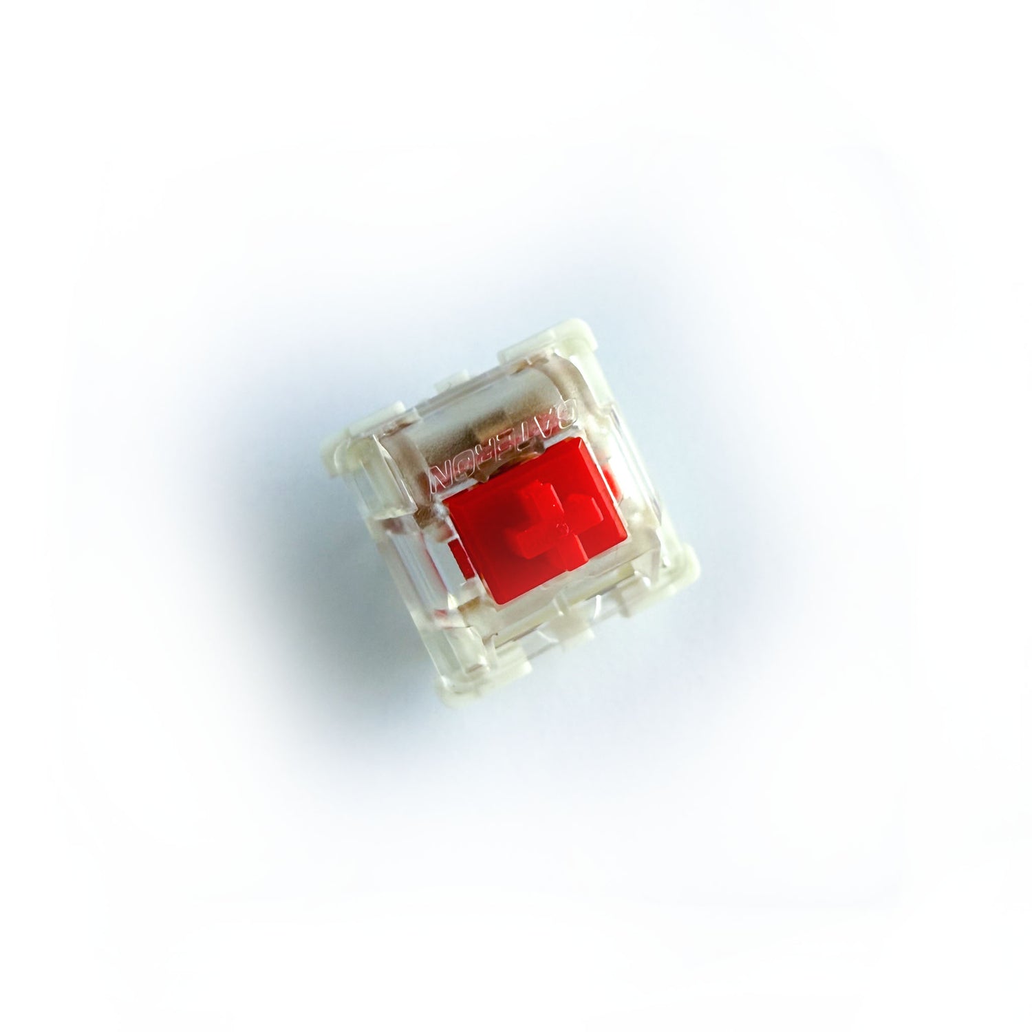 A linear keyboard switch on a white background. The switch component is red, the bottom of the casing is white, and the top of the casing is clear with the word "GATERON" imprinted into it.