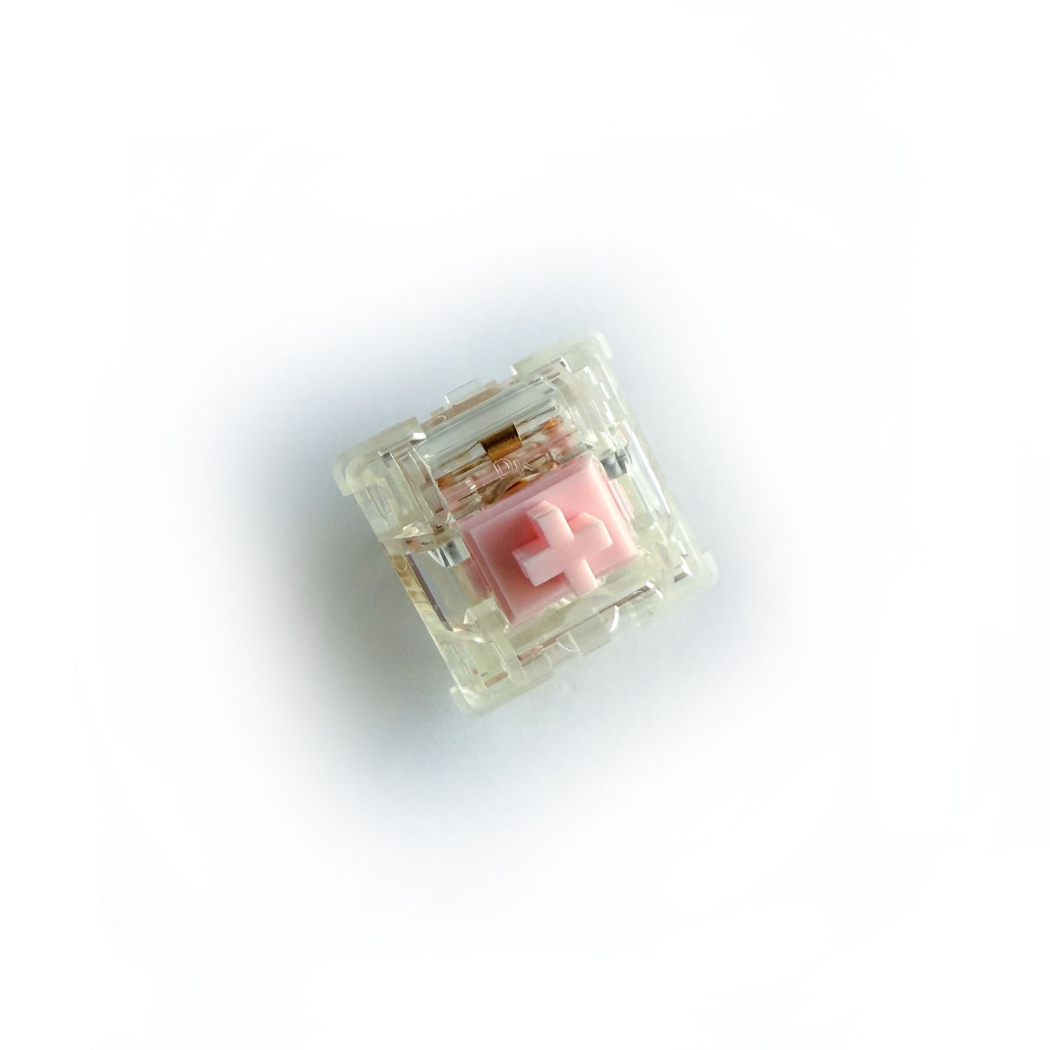 A tactile keyboard switch on a white background. The switch component is light pink, the casing is clear. 