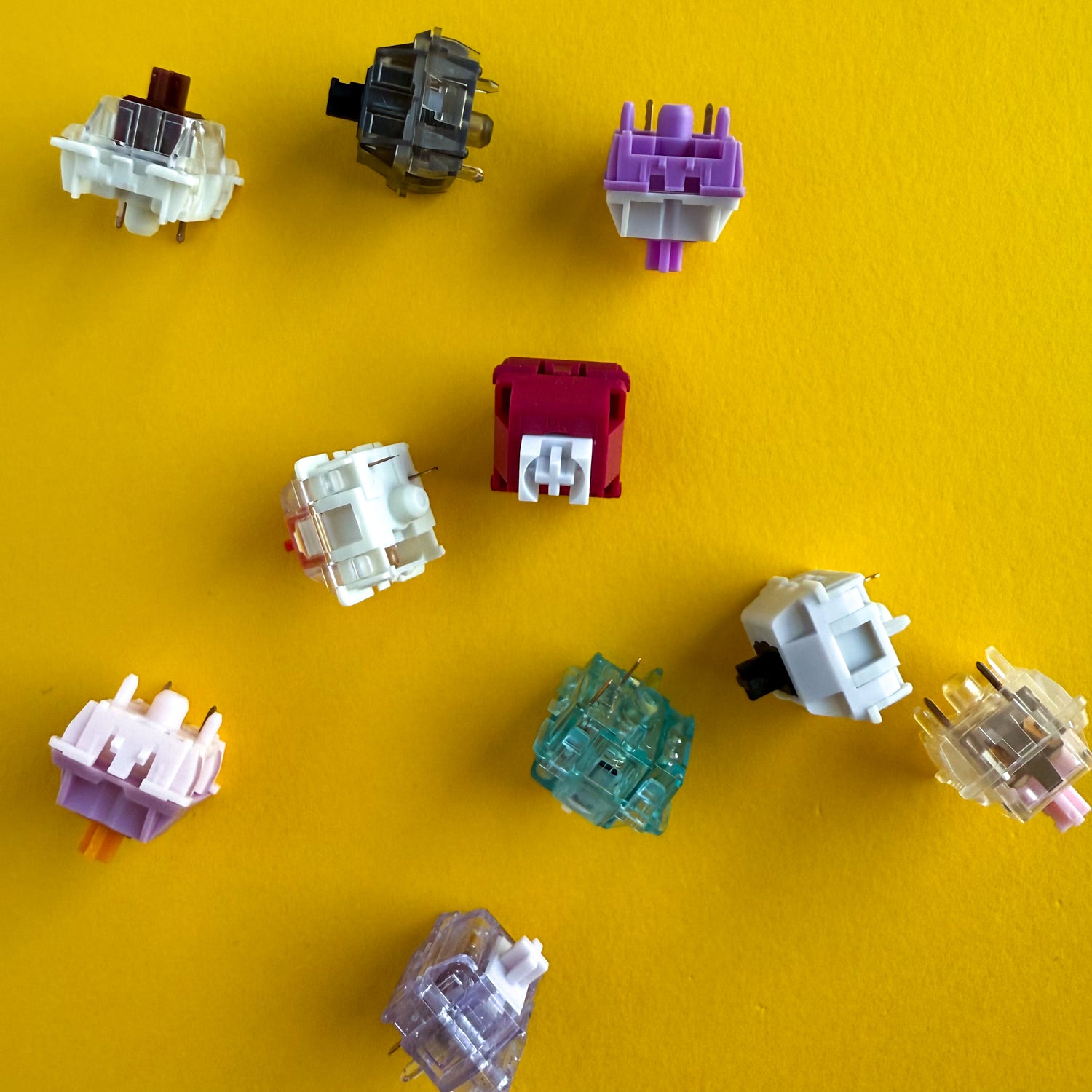 An assortment of different keyboard switches strewn about a yellow background.