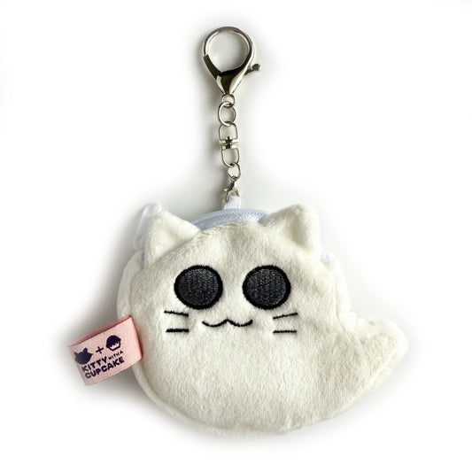 A white fuzzy coin purse with a large lobster claw clasp attached to a small chain coming out of the top. The coin purse is shaped like a floating ghost, but with a cat face complete with large eyes, whiskers, and cat ears. There is a pink tag with the Kitty With a Cupcake logo off the side of the bag.