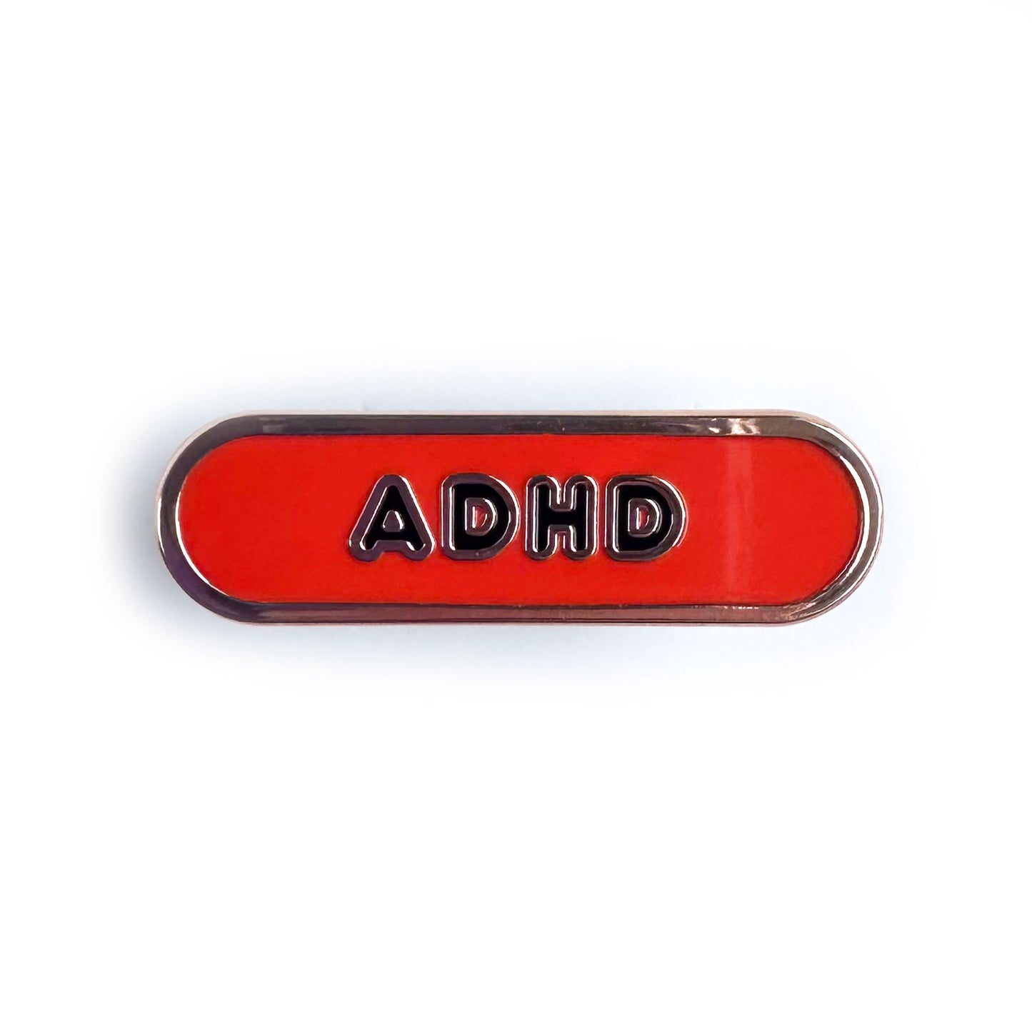 A red oval shaped enamel pin with the letters ADHD on it in black bubble letters.  