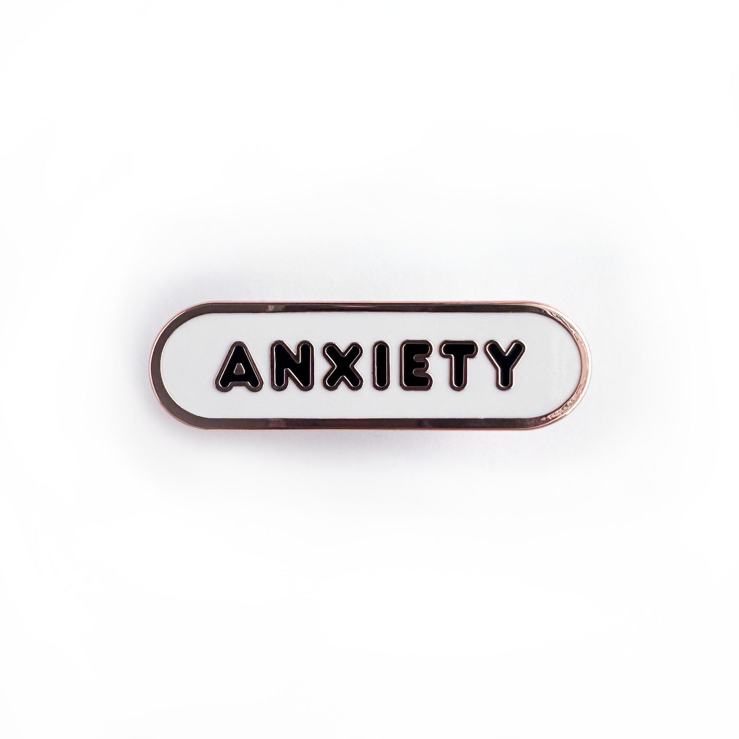 Oval shaped enamel pin with "anxiety" written in black text on a white background.